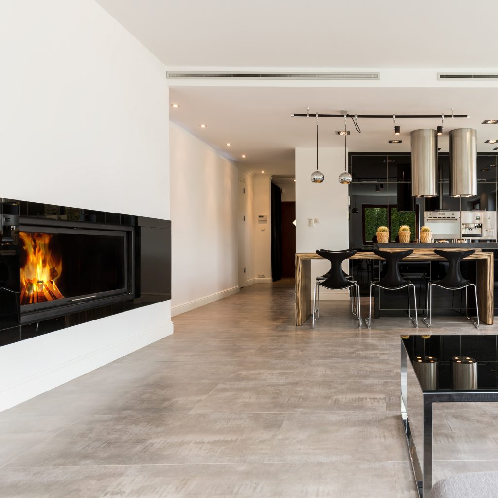 Spacious interior with fireplace, sofa, small table, dining set and black open kitchen
