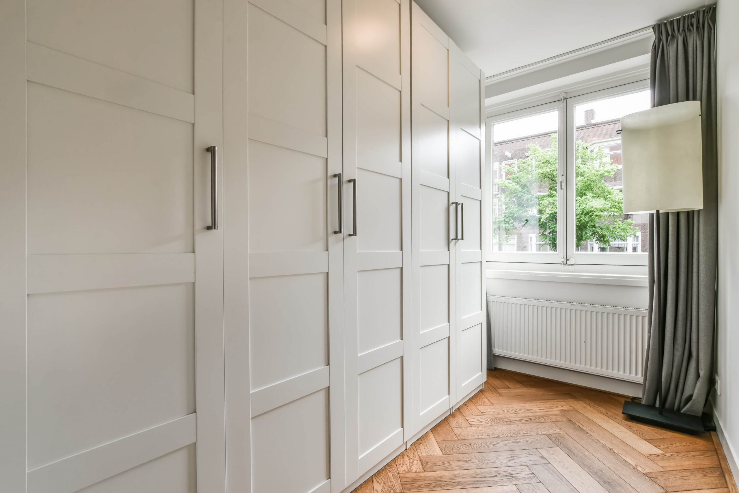 The interior is a minimalist dressing room with large wardrobes and a small window